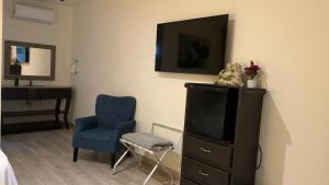 a bedroom with a tv and a blue chair at Hotel Plaza in Sabinas