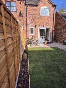 a fence in front of a house with a yard at Bowling Green cottage in Wheaton Aston +13 photos