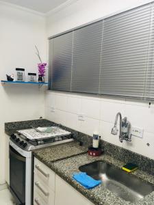 a kitchen with a sink and a stove top oven at Espaço Zen - Equilíbrio da Alma in Guarujá