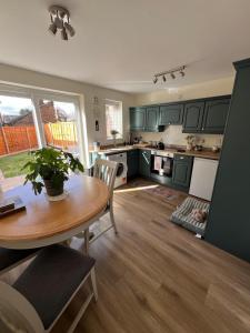 a kitchen with green cabinets and a wooden table at Bowling Green cottage in Wheaton Aston