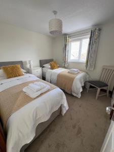 a bedroom with two beds and a chair and a window at Bowling Green cottage in Wheaton Aston