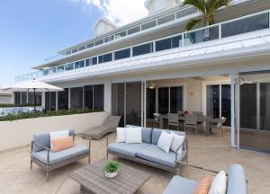 eine Terrasse mit Stühlen und Tischen und ein Gebäude in der Unterkunft South Bay Beach Club #28 - 3Bedroom 2 Bathroom Unit in George Town