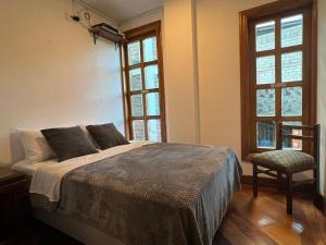 Un dormitorio con una cama y una silla y ventanas. en Villa Pastaza 4 Bedroom 3 Bath, en Baños