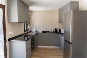 a kitchen with white cabinets and a stainless steel refrigerator at Casa do Moinho in Pampilhosa da Serra