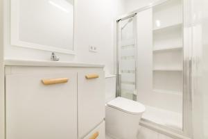 a white bathroom with a toilet and a shower at Buhardilla Encantada in Coslada