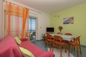 un salon avec un canapé et une table avec des chaises dans l'établissement Apartments by the sea Podgora, Makarska - 23678, à Podgora