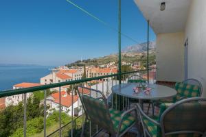 un balcon avec une table et des chaises et l'océan dans l'établissement Apartments by the sea Podgora, Makarska - 23678, à Podgora