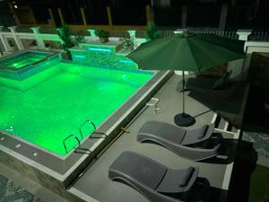a swimming pool with chairs and an umbrella at Benny's Hotel-Inspired & Condo-Inspired Rooms and Pool in Iloilo City