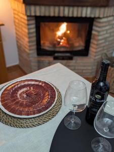 a pie on a table with a bottle of wine and glasses at Casa Corredera in Cumbres Mayores