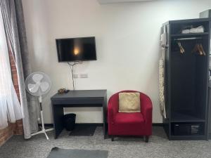 Una habitación con una silla roja, un escritorio y un televisor. en Nottingham CityCentre-Studio-Free Parking-Wifi, en Nottingham