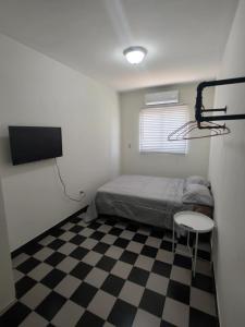 a small bedroom with a bed and a checkerboard floor at Santafe Suites in Hermosillo
