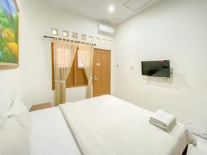 a white room with a bed and a painting on the wall at Hotel Maerakaca Tugu Yogyakarta Mitra RedDoorz in Jetis