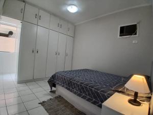 ein Schlafzimmer mit einem Bett und einem Tisch mit einer Lampe in der Unterkunft AP 1 Dorm Ponta da Praia Santos SP in Água Boa