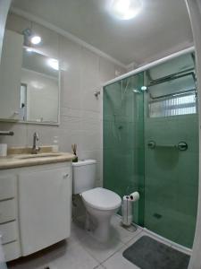 ein Badezimmer mit Toilette und Glasdusche in der Unterkunft AP 1 Dorm Ponta da Praia Santos SP in Água Boa