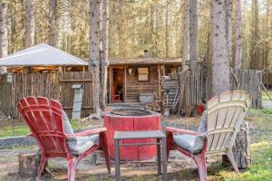 two chairs and a table in front of a cabin at Rustic Cozy Cabin with hot tub in Bragg Creek