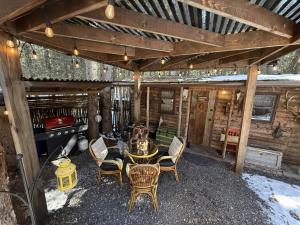 a patio with a table and chairs under a roof at Rustic Cozy Cabin with hot tub in Bragg Creek