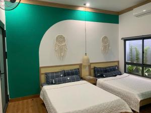 two beds in a room with green and white walls at HomestayHoangYen in Phường Sáu