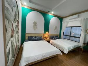 two beds in a room with green and white walls at HomestayHoangYen in Phường Sáu