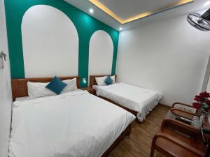 two beds in a room with green and white walls at HomestayHoangYen in Phường Sáu
