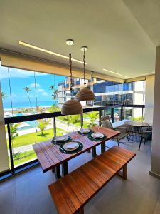 a dining room with a table and a large window at Sofisticação e Luxo à Beira-mar no Cais Eco em Muro Alto by HM in Porto De Galinhas