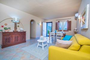 Una sala de estar con un sofá amarillo y una mesa. en La Dimora di Amaranta, en Baja Sardinia