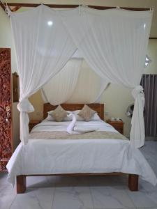 a bedroom with a canopy bed with white curtains at Kelle Homestay in Sidemen