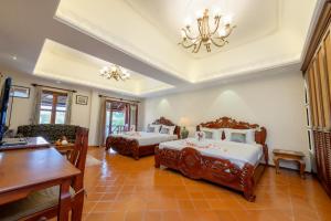 a large room with two beds and a table at Villa Deux Rivieres Hotel in Luang Prabang