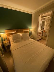 una camera da letto con un grande letto bianco con una parete verde di Azuria a Cannes