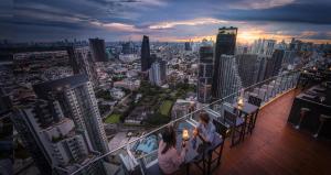 two people sitting on a balcony of a city skyline at Bangkok Marriott Hotel Sukhumvit in Bangkok