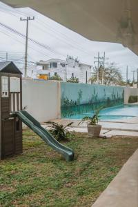 a slide in a yard next to a swimming pool at Depto de Playa con vista Alberca in Chicxulub