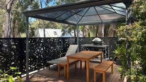 a patio with a table and benches and a grill at Kingfisher Loft in Daylesford