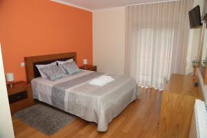 a bedroom with a bed with an orange wall at BellaVista Alojamento in Arouca