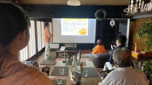 a man giving a presentation to a group of people at 古民家ウェルネスビレッジ青梅 成木の社 Nariki no Mori in Ome