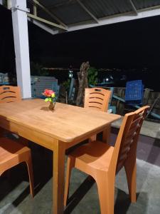 a wooden table with chairs and a vase with flowers on it at Blesshi Guest House Bunaken in Bunaken