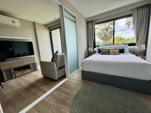 Un dormitorio con una cama, un televisor y una silla. en Diamond apartaments 700m BangTao beach, en Bang Tao Beach