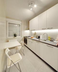 a kitchen with white cabinets and a table and chairs at Apartment Osijek-Tvrda in Osijek