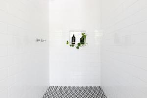 Un baño con azulejos blancos y una planta en un estante. en StayByronBay - The Little French Salon de la Sirène and Scandinavian Simplicity Byron Bay, en Byron Bay