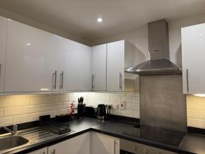 a kitchen with white cabinets and a sink at Apartment near Luton Airport, Train Station & Football Club in Luton