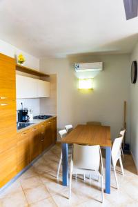 Una cocina con una mesa de madera y sillas blancas. en Aparthotel Tropical Bounty Beach B11, en Santa Maria