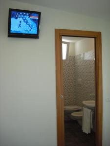 a bathroom with a toilet and a television on the wall at Hotel Belmar in Cattolica