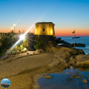 a lighthouse on a beach with a bench in front at Sweet home in Casa Santa +6 photos