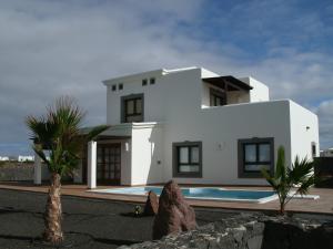 a white house with a swimming pool in front of it at Villas Coral Deluxe in Playa Blanca