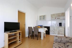 uma sala de estar com uma mesa com cadeiras e uma televisão em Apartments Olga em Božava