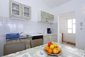 a kitchen with a bowl of fruit on a table at Apartments Olga in Božava