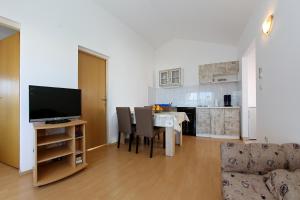 a living room with a table with chairs and a television at Apartments Olga in Božava