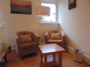 a living room with two chairs and a table at Woodside Guest House in Stornoway