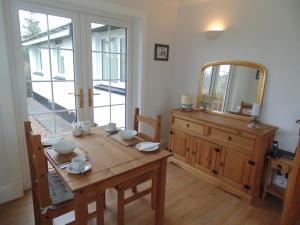 a dining room with a wooden table and a mirror at Woodside Guest House in Stornoway