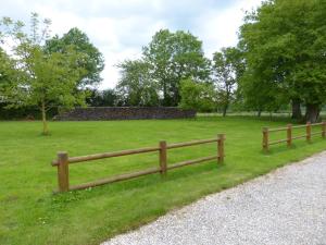 a wooden fence in the grass next to a field at Les Baillis in Villegenon