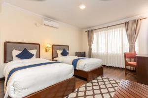a hotel room with two beds and a chair at Kathmandu Business Hotel in Kathmandu