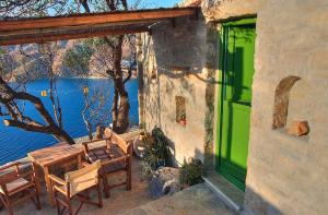 a building with a green door and tables and chairs at Pano Gitonia in Aegiali